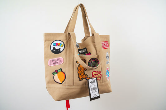Checkered tote bag with various patches and a visible Vans tag.